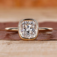 Cushion cut engagement ring with bezel set ring.