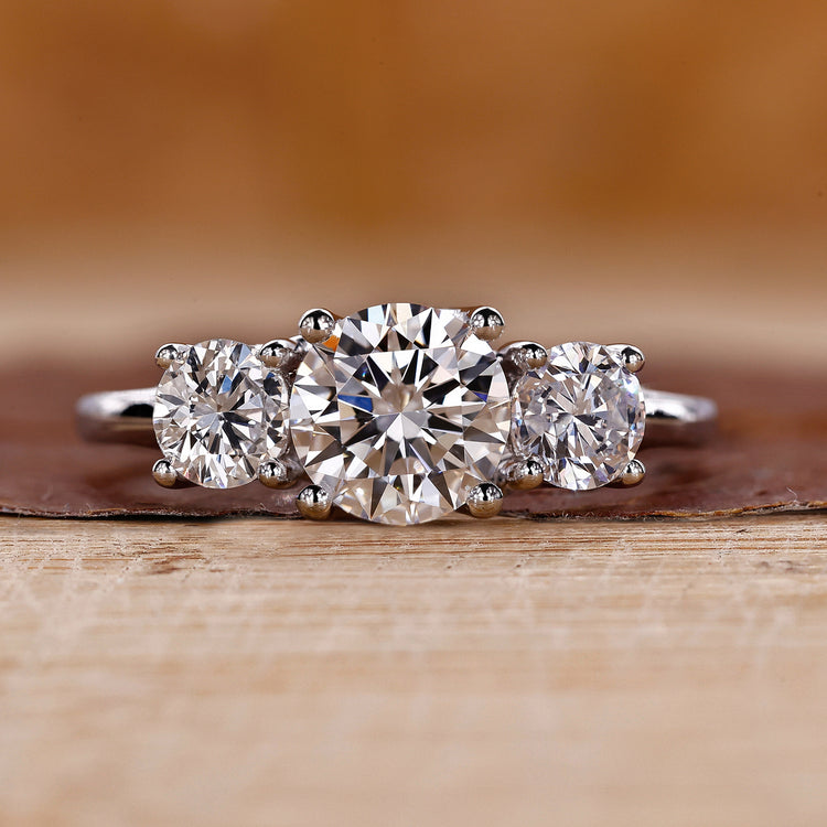 Three stone engagement ring crafted in a white gold trellis ring setting.