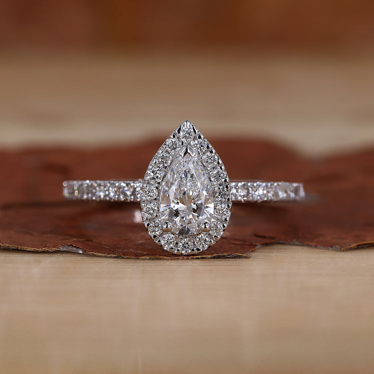 Pear halo engagement ring with round cut pave band.