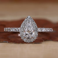 Pear halo engagement ring with round cut pave band.