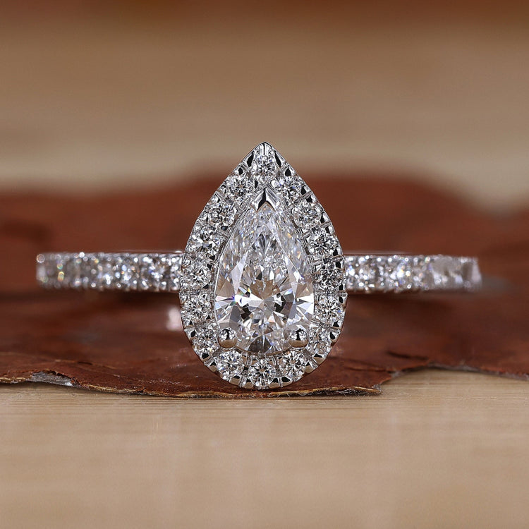 Pear halo engagement ring with round cut pave band.