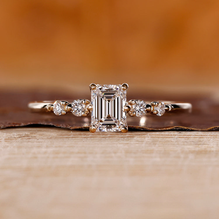 Emerald Cut Diamond Ring with round side stones and tapered shank.