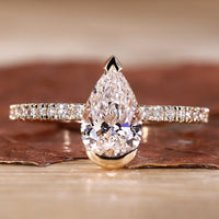 Close-up of a pear shaped ring in yellow gold with a half bezel setting, showcasing its unique design.