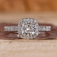 Cushion cut halo engagement ring with round diamond halo in yellow gold.