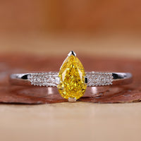 Yellow diamond pear engagement ring with pave diamond band.