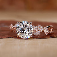 Nature-inspired engagement ring with a round brilliant cut diamond, featuring a tulip setting and claw prongs.