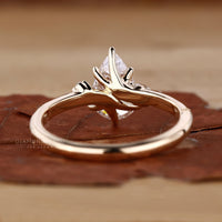 Detailed view of pear cut diamond ring featuring claw prongs and marquise sidestone.