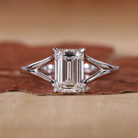 Close-up of emerald cut solitaire ring with claw prongs and white gold band.