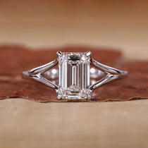 Close-up of emerald cut solitaire ring with claw prongs and white gold band.