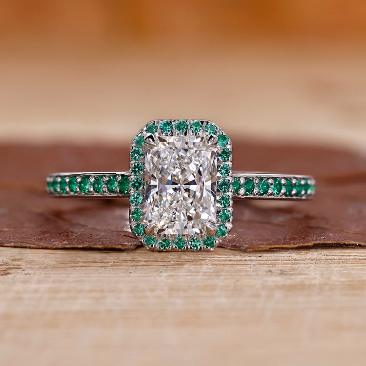 Radiant cut diamond ring with round cut emerald and claw prong setting in white gold.