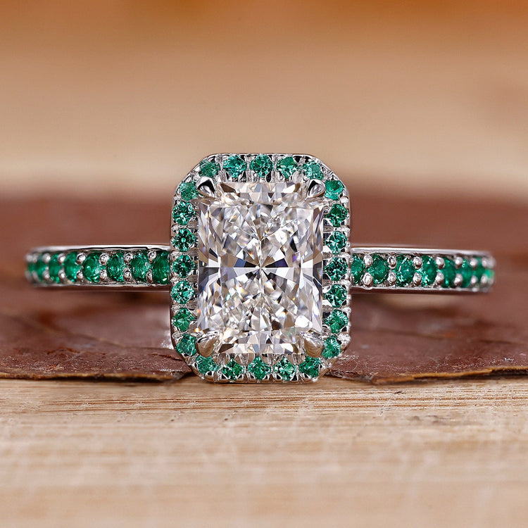 Radiant cut diamond ring with round cut emerald and claw prong setting in white gold.