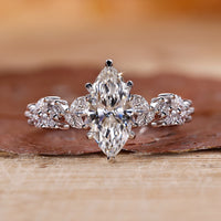 Marquise cut engagement ring with round side stones in white gold.