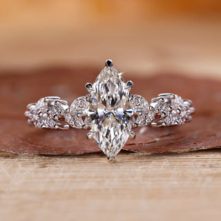 Marquise cut engagement ring with round side stones in white gold.
