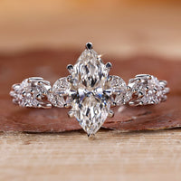 Marquise cut engagement ring with round side stones in white gold.