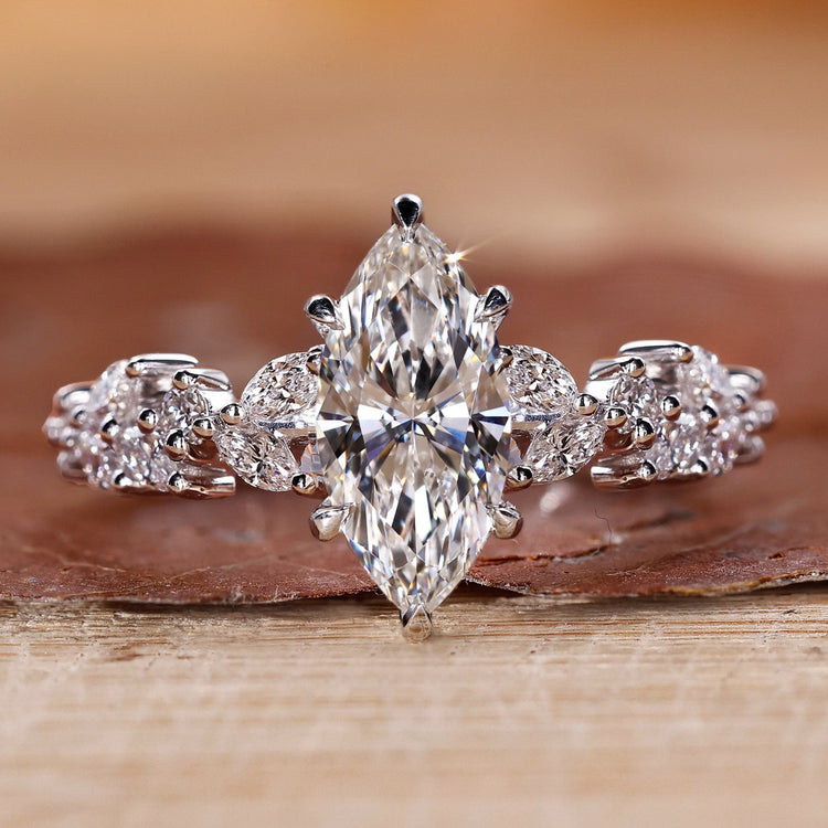 Marquise cut engagement ring with round side stones in white gold.