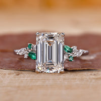 Emerald cut diamond engagement ring with round and marquise side stones.