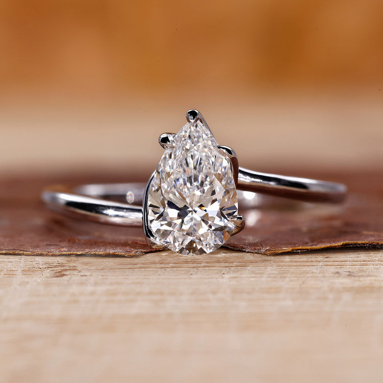 Twisted engagement ring with pear cut diamond in a claw prong setting crafted in white gold.