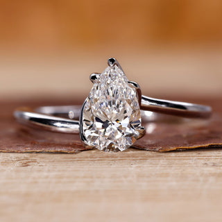 Twisted engagement ring with pear cut diamond in a claw prong setting crafted in white gold.