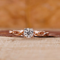 Solitaire diamond ring with round cut diamond and twisted shank in rose gold.