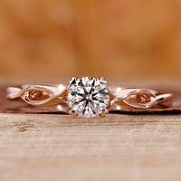Solitaire diamond ring with round cut diamond and twisted shank in rose gold.