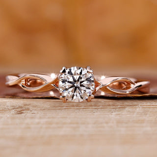 Solitaire diamond ring with round cut diamond and twisted shank in rose gold.