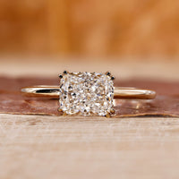 Elongated cushion cut diamond ring with double claw prong in yellow gold.