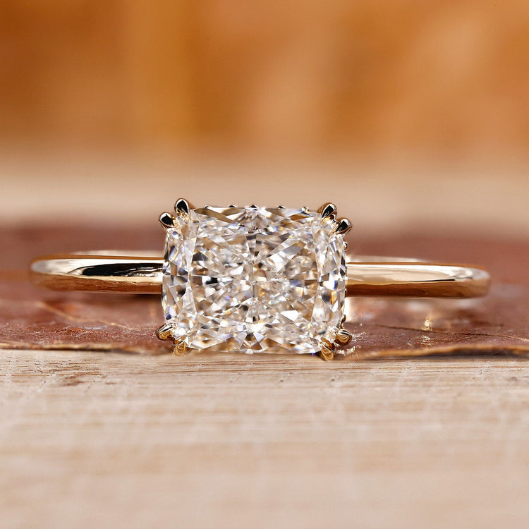 Elongated cushion cut diamond ring with double claw prong in yellow gold.