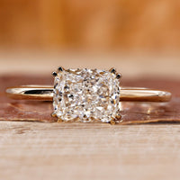 Elongated cushion cut diamond ring with double claw prong in yellow gold.