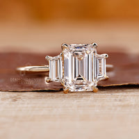 Yellow gold engagement ring with three stone emerald cut ring.