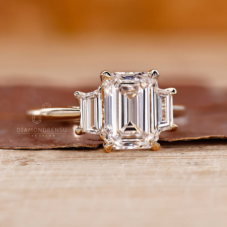 Yellow gold engagement ring with three stone emerald cut ring.
