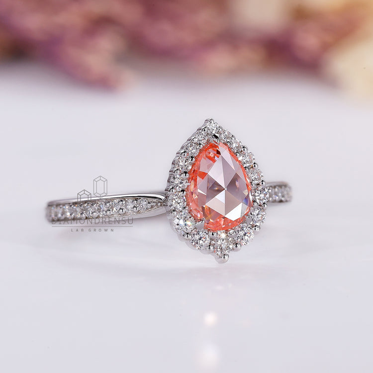 Round diamond halo ring with pink pear diamond and pavé details.