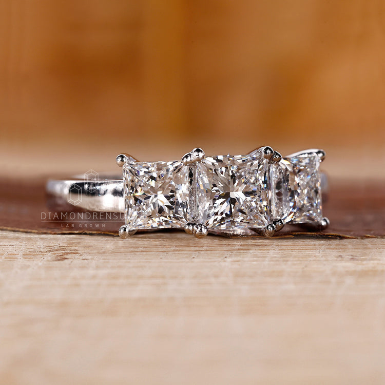 White gold ring with a princess cut centre and side stones.