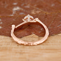 Custom diamond ring in rose gold with round cut and side stones.