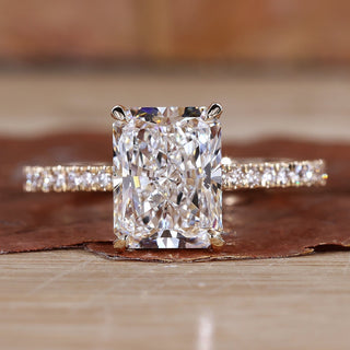 Radiant cut diamond ring with pave diamonds in yellow gold, featuring hidden halo engagement ring design and claw prongs