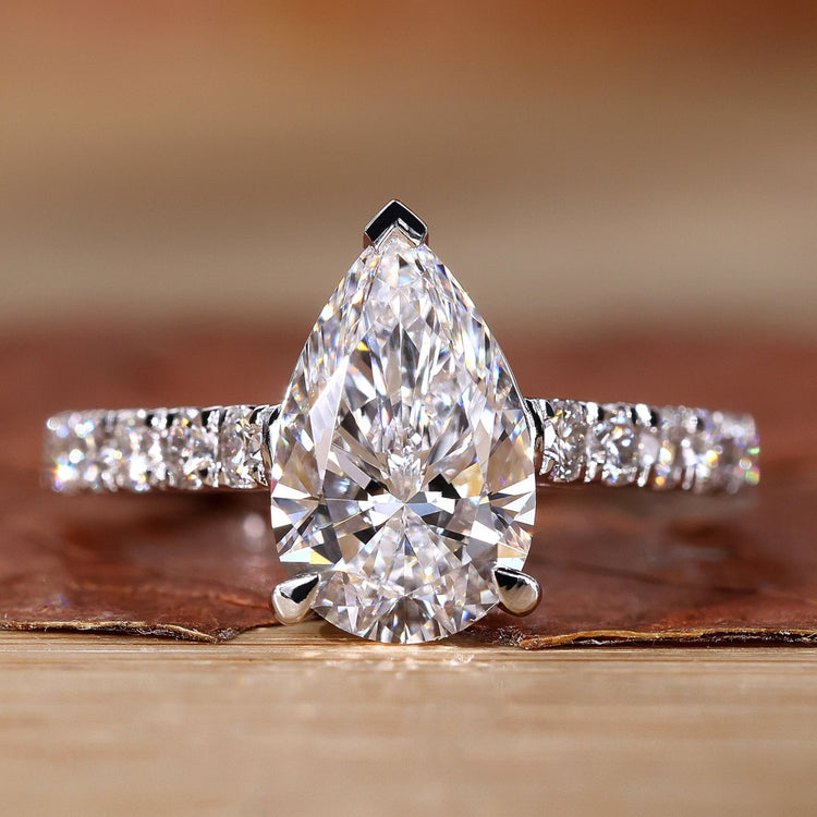 Close-up of a pear shaped diamond ring with pave diamond accents