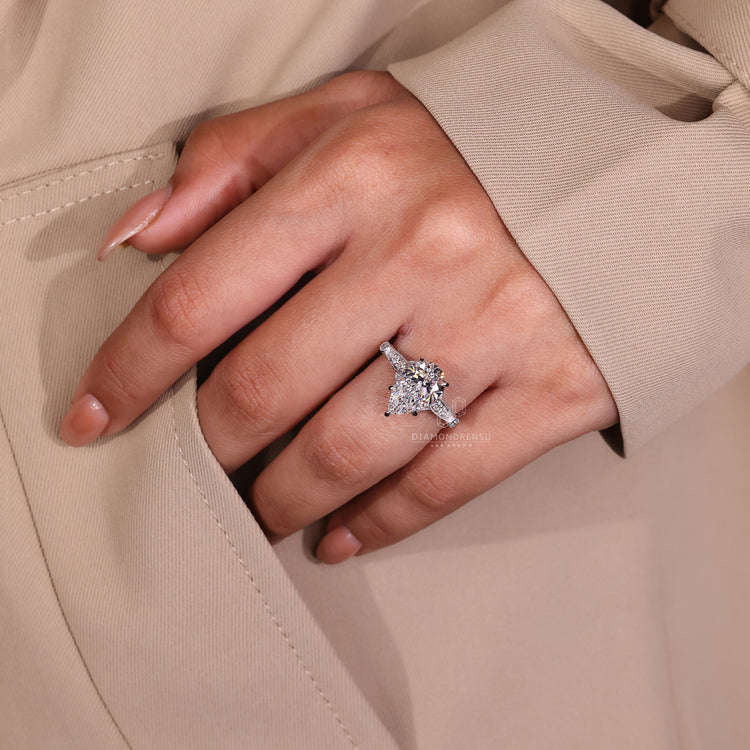 Cathedral setting ring with pear diamond and round side stones.