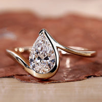 Pear shaped engagement ring in yellow gold with a unique design