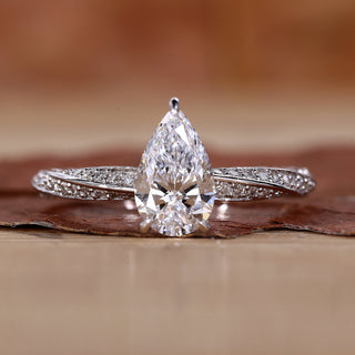 Close-up of a pear shaped diamond ring featuring twisted diamond pave