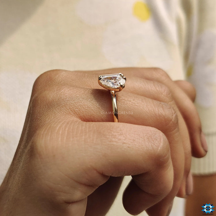 Claw prong setting secures the emerald and pear shaped stones.