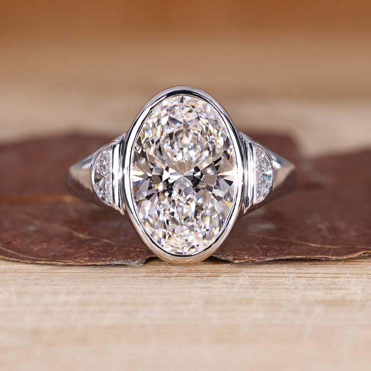 Oval cut diamond ring with half moon side stone.