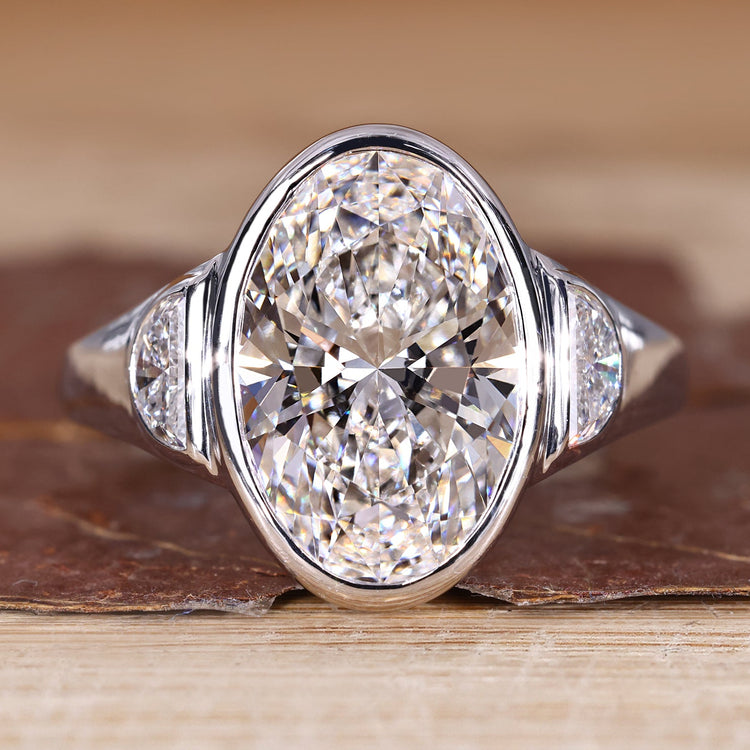 Oval cut diamond ring with half moon side stone.