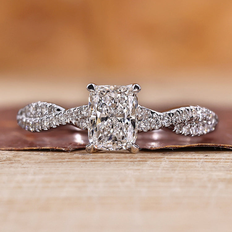 Elongated cushion cut diamond ring with twisted pave band.
