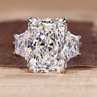 3 stone radiant cut ring with trapezoid side stone and cathedral setting.
