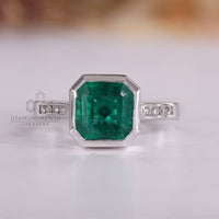 Asscher cut emerald gemstone ring bezel channel set.