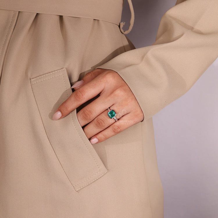 Emerald gemstone ring channel diamonds bezel set.