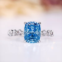 Cushion cut diamond ring with blue sapphire accent.