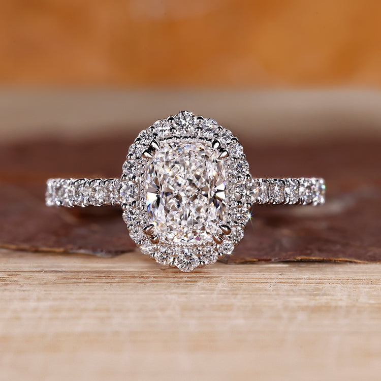 Elongated cushion cut diamond ring with round diamond halo setting.