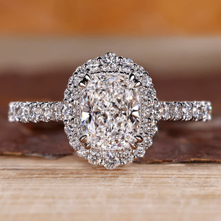 Elongated cushion cut diamond ring with round diamond halo setting.