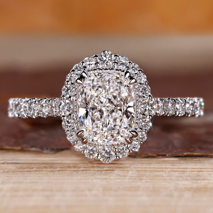 Elongated cushion cut diamond ring with round diamond halo setting.