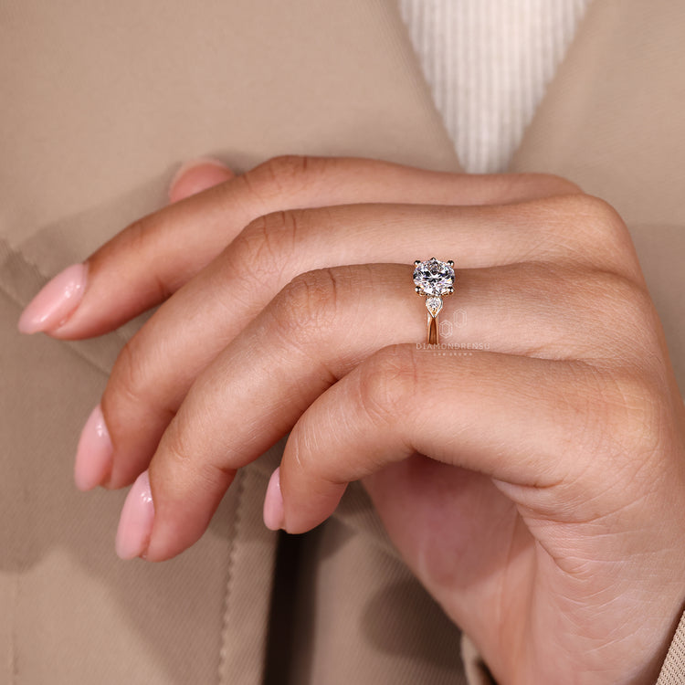 Three stone round diamond ring with pear outline detail.